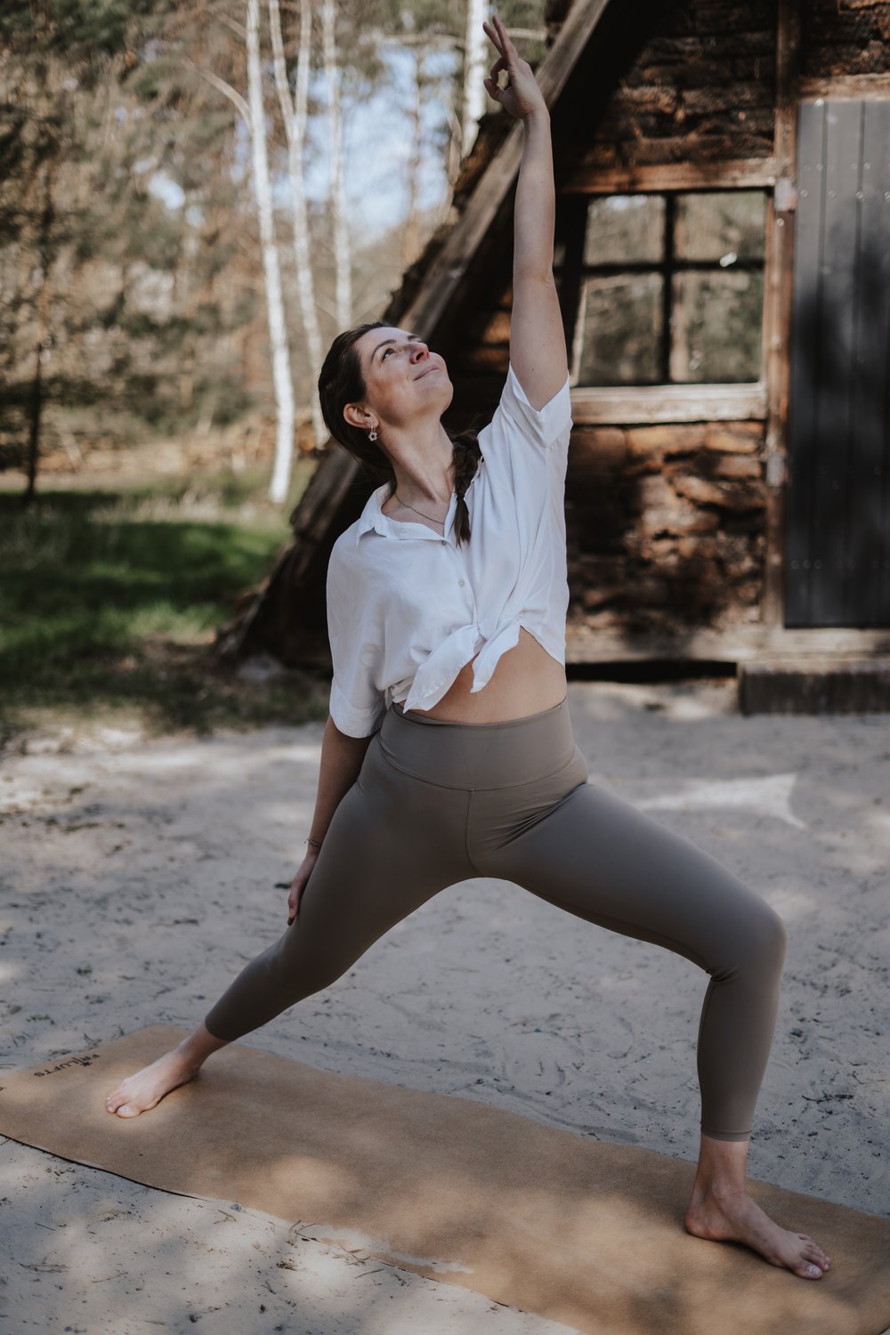 Fabienne von Gahlen in Warrior-Pose vor Hütte im Wald – Yoga-Begleitung